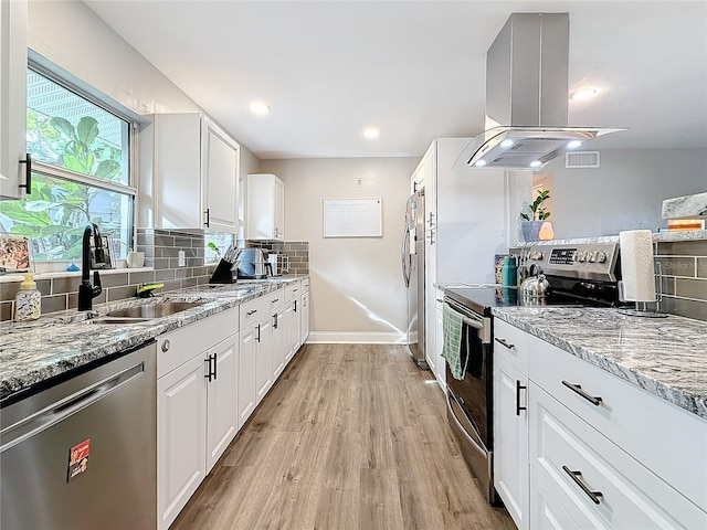 kitchen with stainless steel appliances, island exhaust hood, sink, and white cabinetry