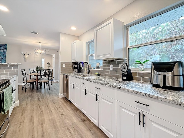 kitchen featuring sink, white cabinetry, light hardwood / wood-style flooring, pendant lighting, and backsplash