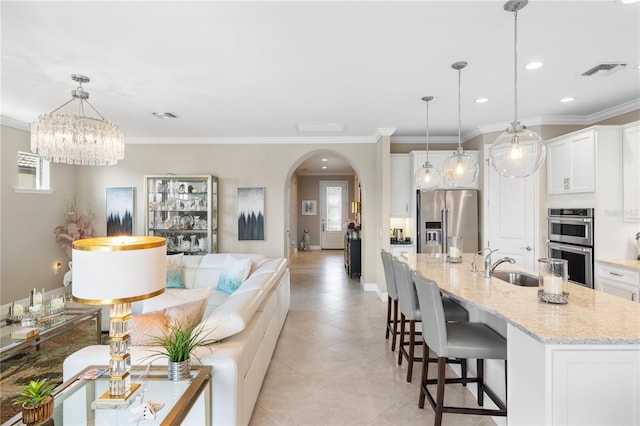 kitchen with a center island with sink, white cabinetry, appliances with stainless steel finishes, and pendant lighting