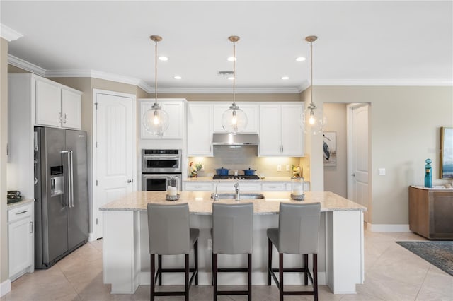 kitchen with hanging light fixtures, appliances with stainless steel finishes, and a center island with sink