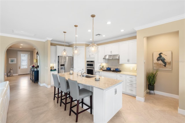 kitchen with white cabinetry, stainless steel appliances, a kitchen island with sink, and hanging light fixtures