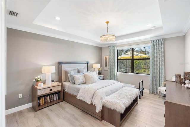 bedroom with ornamental molding, a raised ceiling, light hardwood / wood-style floors, and a notable chandelier