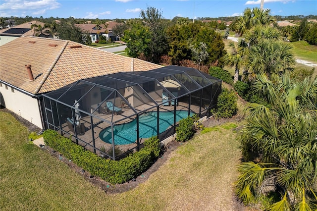 view of pool with a lawn, a patio, and glass enclosure