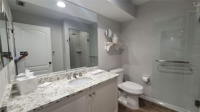 bathroom featuring vanity, wood-type flooring, toilet, and a shower with shower door