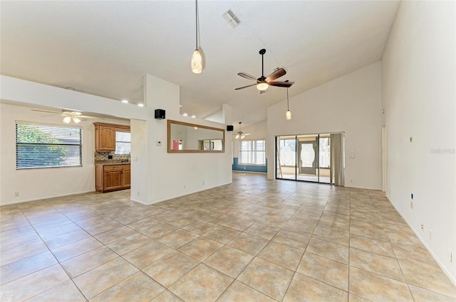 unfurnished living room featuring light tile patterned floors, high vaulted ceiling, a healthy amount of sunlight, and ceiling fan