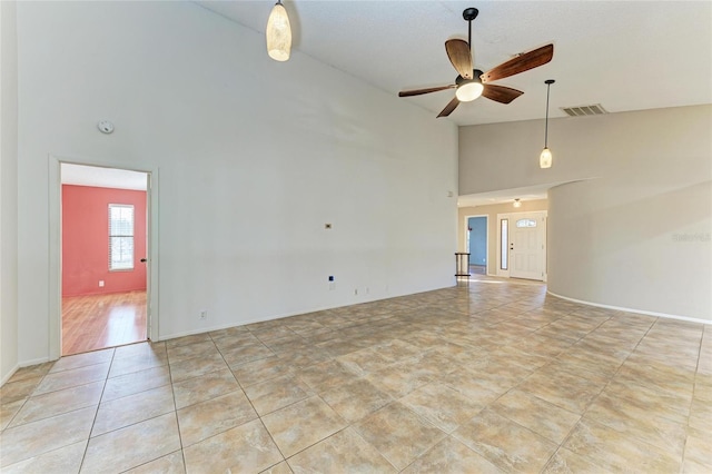 empty room featuring ceiling fan, light tile patterned floors, and high vaulted ceiling