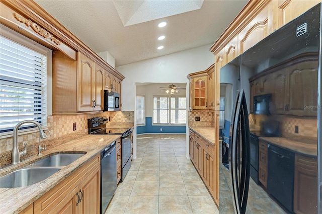 kitchen with light tile patterned flooring, lofted ceiling with skylight, sink, backsplash, and black appliances