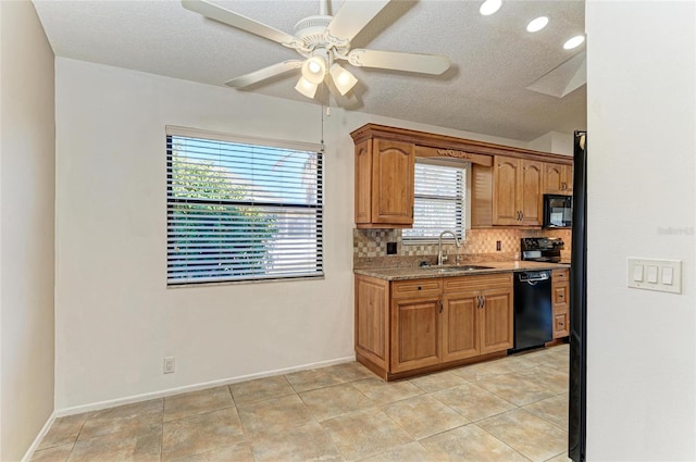 kitchen with sink, black appliances, a textured ceiling, light stone countertops, and backsplash