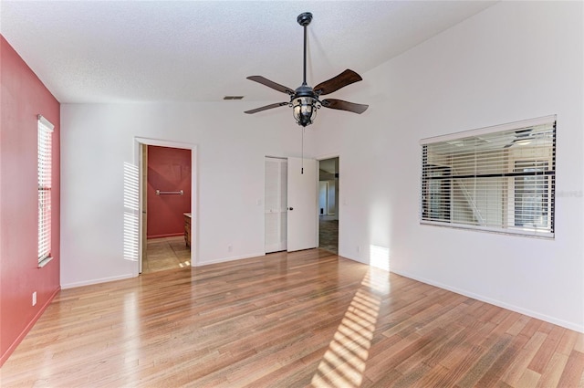 spare room featuring vaulted ceiling, ceiling fan, a textured ceiling, and light hardwood / wood-style flooring