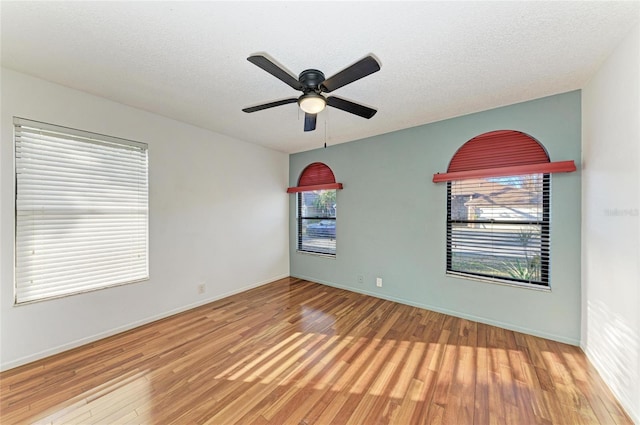 empty room with ceiling fan, wood-type flooring, and a textured ceiling