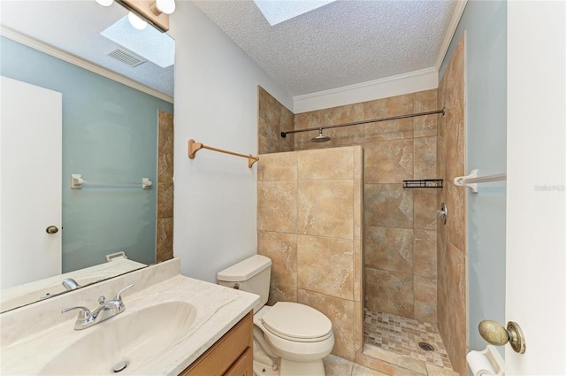 bathroom with tiled shower, toilet, a skylight, and a textured ceiling