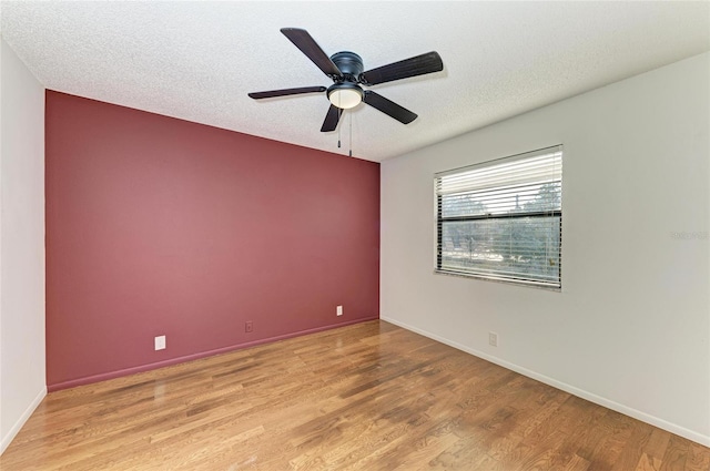 empty room with ceiling fan, a textured ceiling, and light wood-type flooring