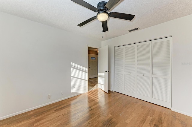 unfurnished bedroom with ceiling fan, a textured ceiling, light wood-type flooring, and a closet