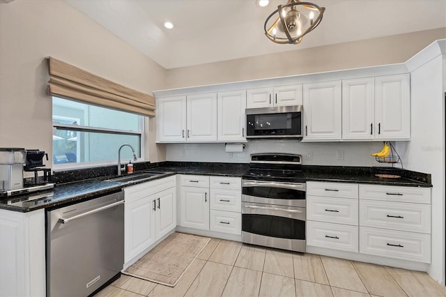 kitchen with stainless steel appliances, sink, dark stone counters, and white cabinets