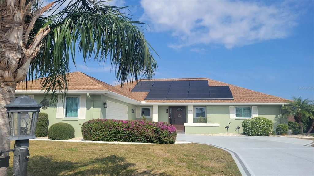 ranch-style house with a garage, a front lawn, and solar panels