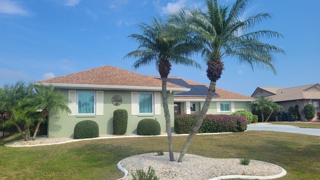 ranch-style house with a front yard and solar panels