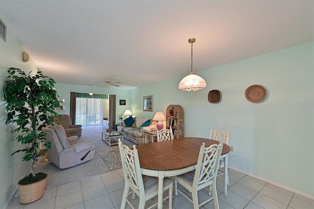 tiled dining area with ceiling fan and a textured ceiling