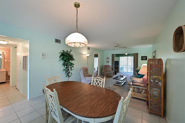 tiled dining area with ceiling fan and a textured ceiling