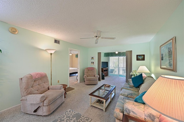 living room with ceiling fan, light colored carpet, and a textured ceiling