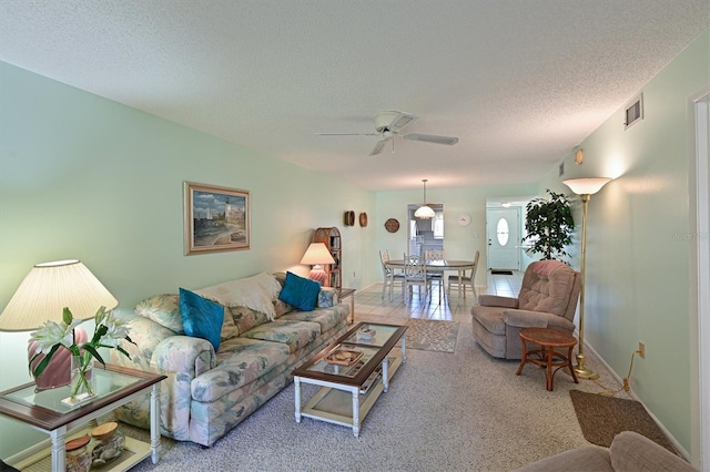 carpeted living room with ceiling fan and a textured ceiling