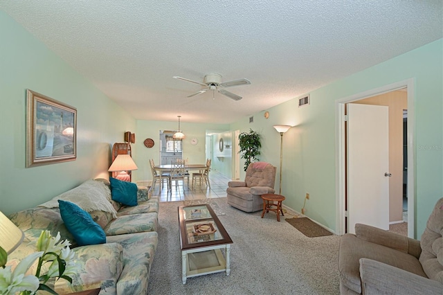 living room with ceiling fan, a textured ceiling, and carpet flooring