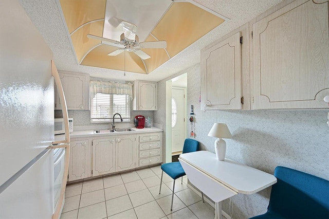 kitchen with light tile patterned flooring, sink, ceiling fan, a raised ceiling, and white appliances