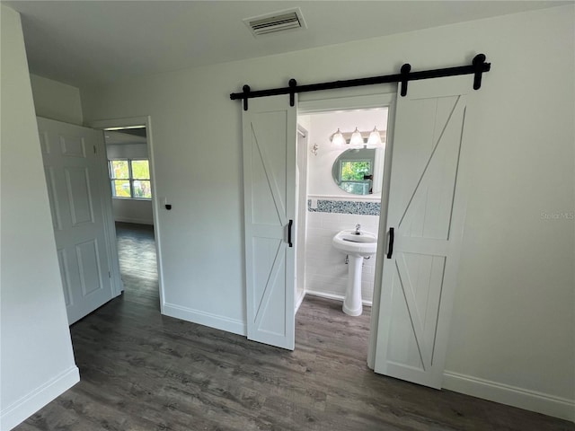 interior space featuring tile walls, dark wood-type flooring, and a barn door