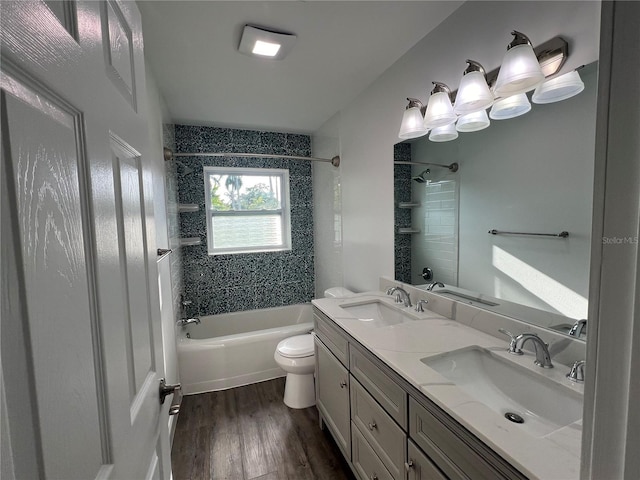 full bathroom featuring hardwood / wood-style flooring, tiled shower / bath, vanity, and toilet