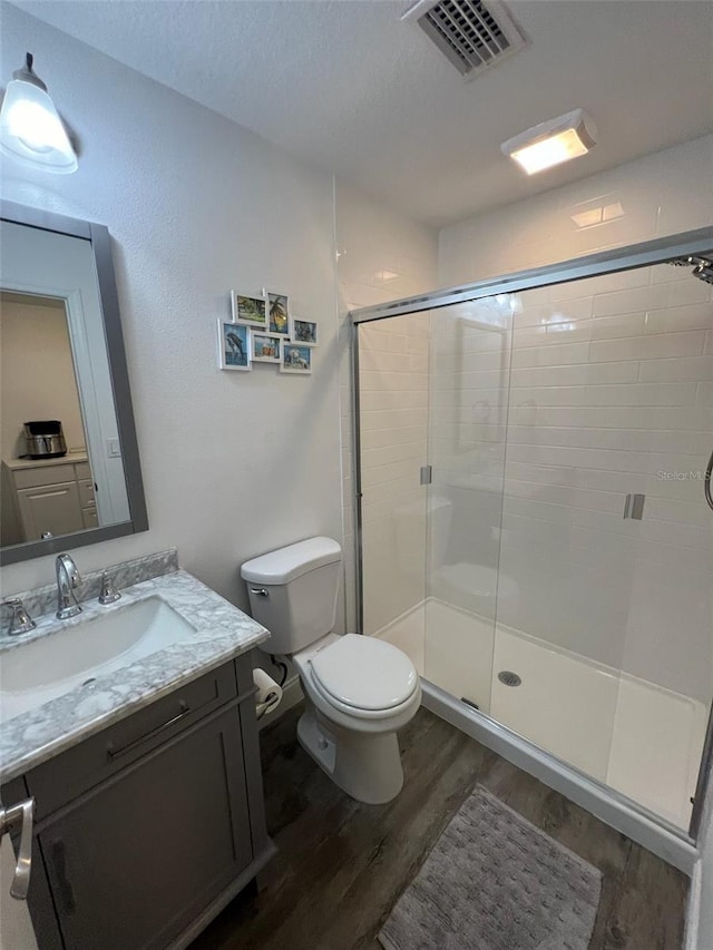 bathroom featuring hardwood / wood-style flooring, vanity, toilet, and a shower with door