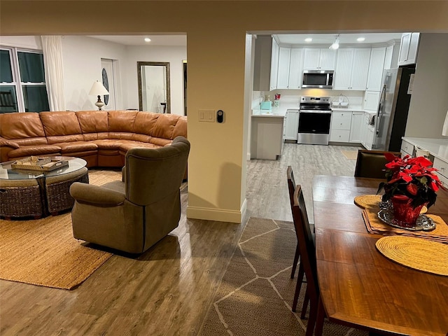 interior space featuring appliances with stainless steel finishes, wood-type flooring, and white cabinets