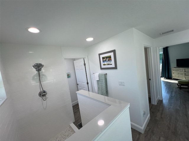 bathroom featuring wood-type flooring and a tile shower