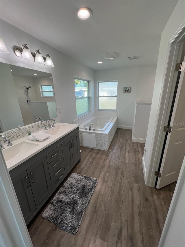 bathroom featuring vanity, wood-type flooring, and tiled bath