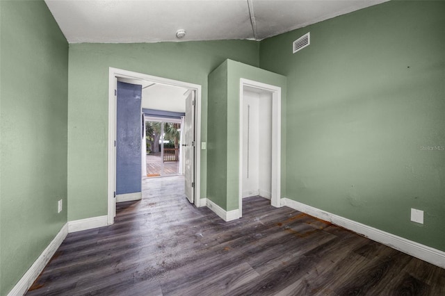 empty room featuring vaulted ceiling and dark hardwood / wood-style floors