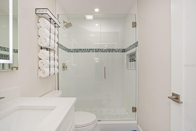 bathroom featuring vanity, a shower with door, and toilet