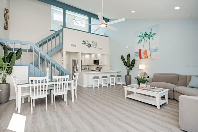 living room featuring ceiling fan, high vaulted ceiling, and light wood-type flooring