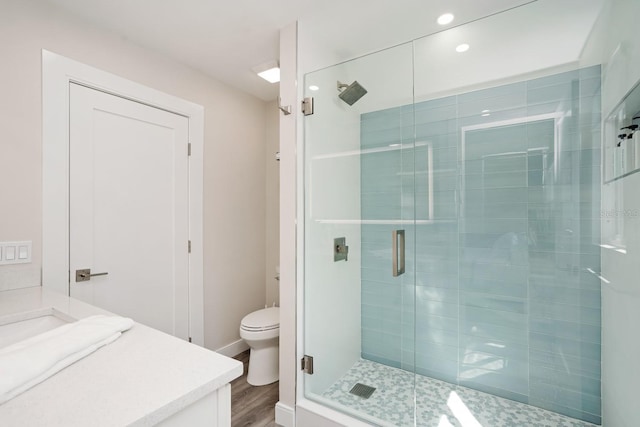 bathroom featuring vanity, wood-type flooring, walk in shower, and toilet