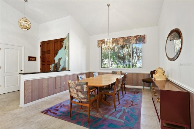 dining space with lofted ceiling, a notable chandelier, and wood walls