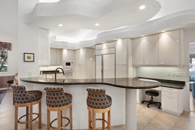 kitchen featuring white cabinetry, built in desk, white appliances, and decorative backsplash