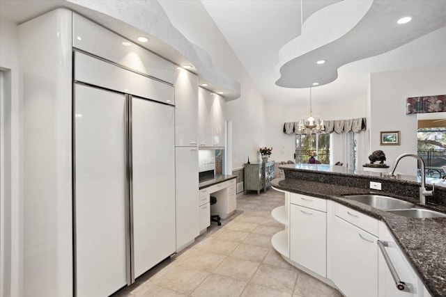 kitchen featuring hanging light fixtures, white cabinetry, sink, and paneled built in fridge