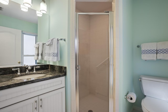 bathroom with vanity, toilet, and a shower with door