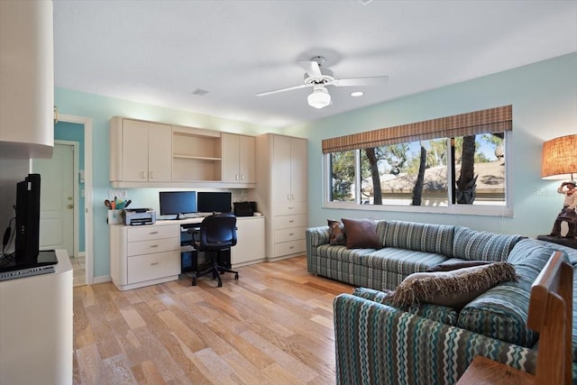 office space with ceiling fan, built in desk, and light hardwood / wood-style floors