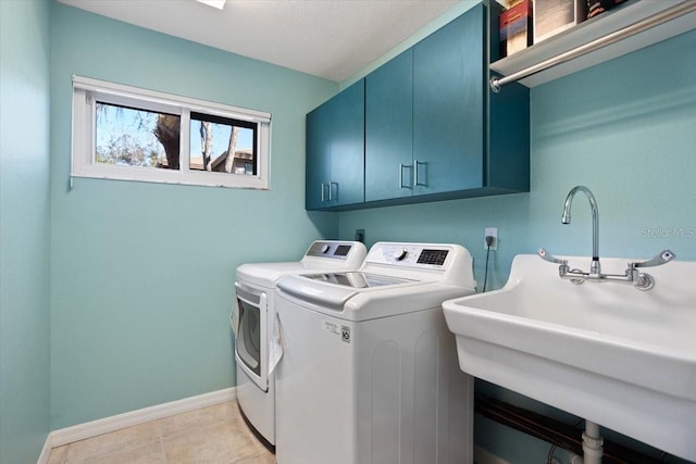 laundry area with sink, light tile patterned floors, washing machine and dryer, and cabinets