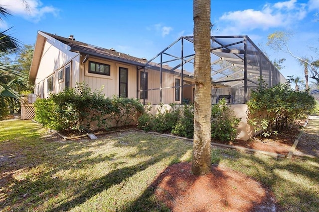 rear view of property featuring a yard and glass enclosure