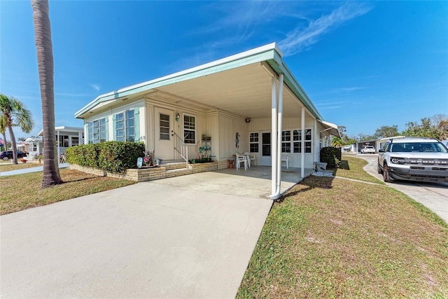 manufactured / mobile home with a carport and a front yard