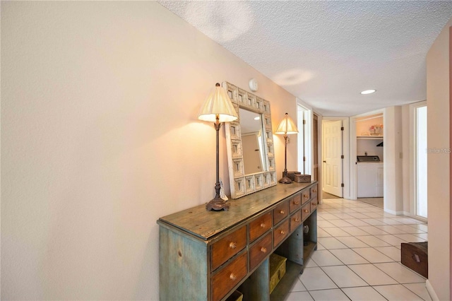 hallway featuring washer / dryer, a textured ceiling, and light tile patterned floors