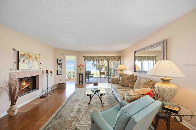 living room with wood-type flooring, a textured ceiling, and a fireplace