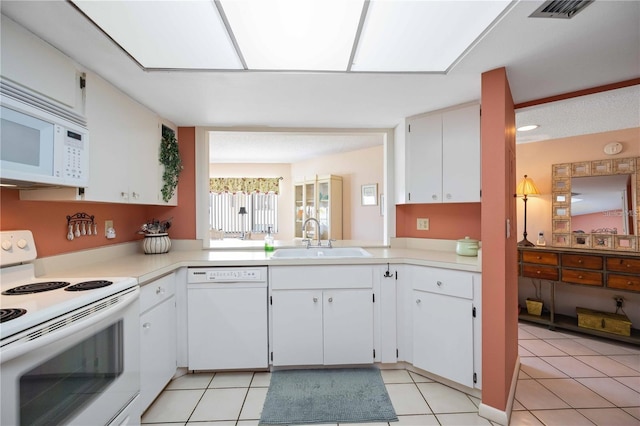 kitchen with sink, white appliances, light tile patterned floors, and white cabinets