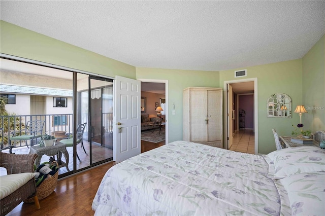 bedroom with dark hardwood / wood-style flooring, access to outside, and a textured ceiling