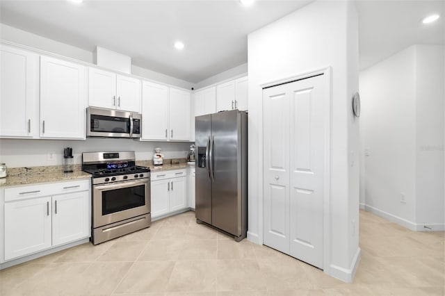 kitchen featuring white cabinetry, appliances with stainless steel finishes, light tile patterned floors, and light stone counters