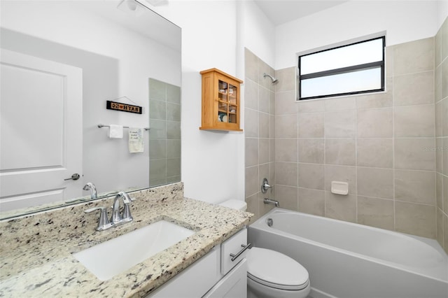 full bathroom with tiled shower / bath, vanity, and toilet